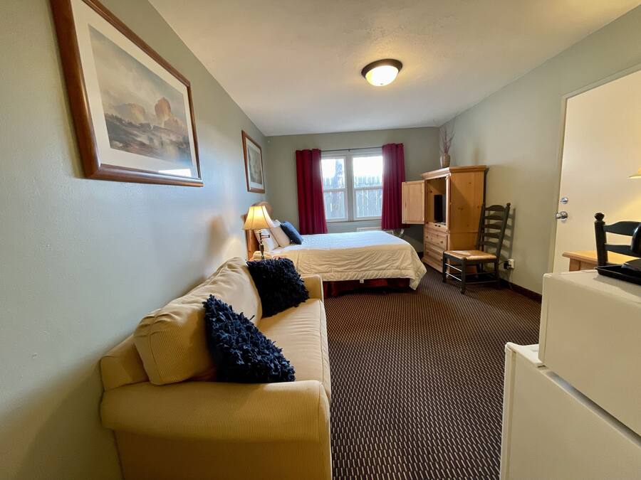 Una habitación de hotel con cama, sofá, cómoda y escritorio.
