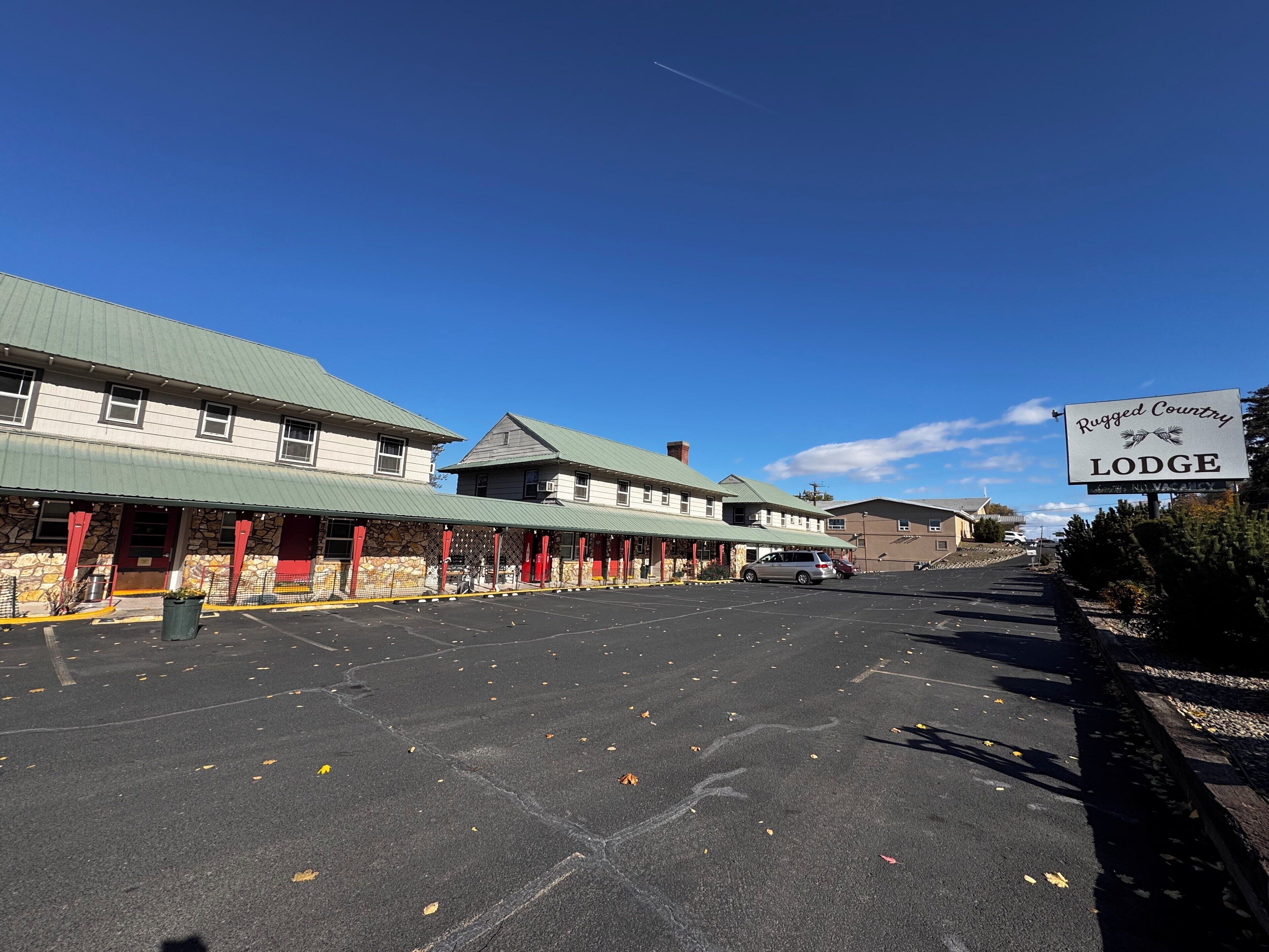 Un estacionamiento frente a un edificio con un letrero que dice 'Rugged Country Lodge'.