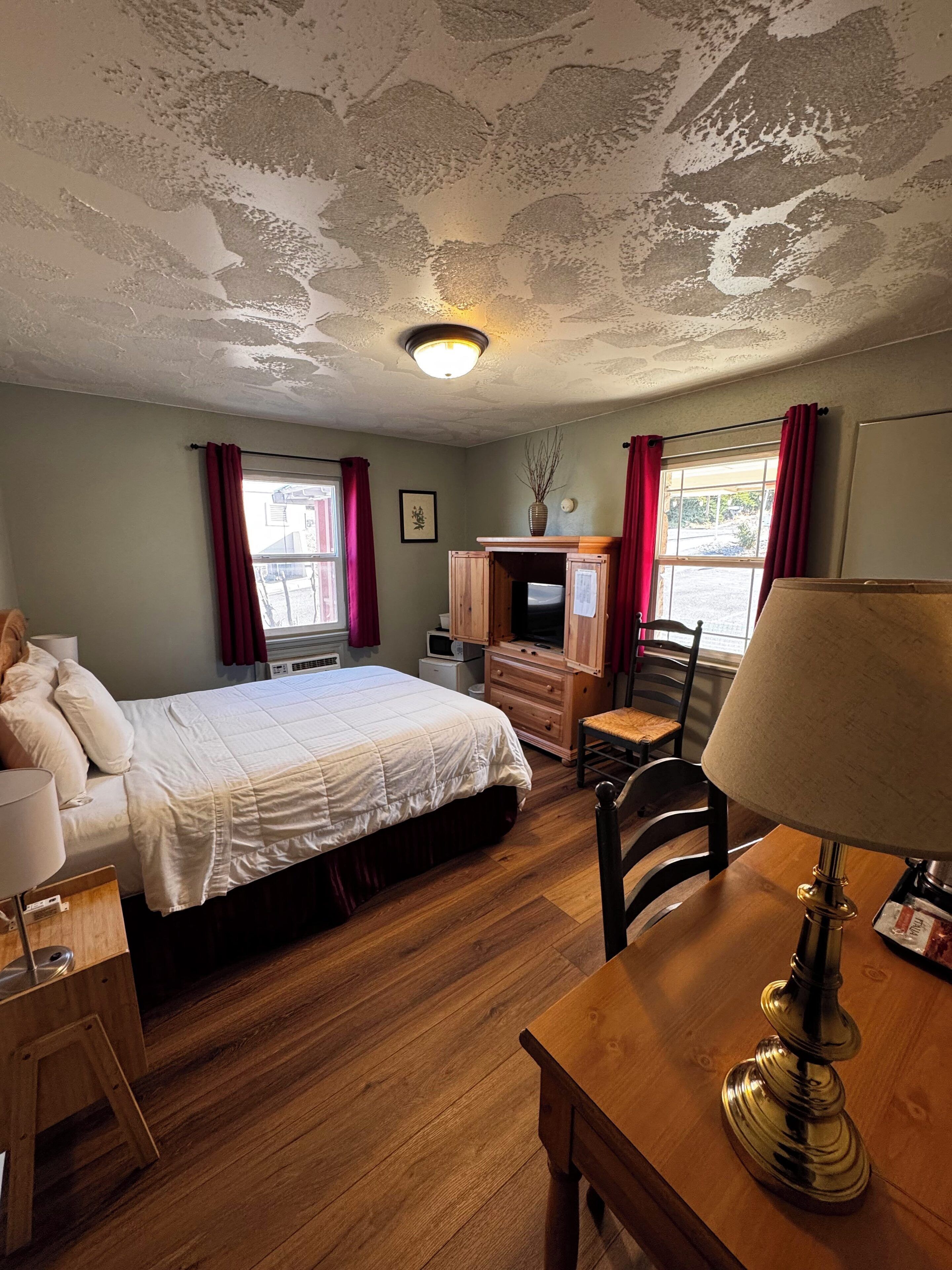 A room with a bed, a desk, a lamp, a TV, and a fireplace.