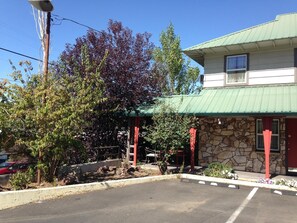 A building with a stone facade and a green roof, a parking lot, and trees with autumn foliage.