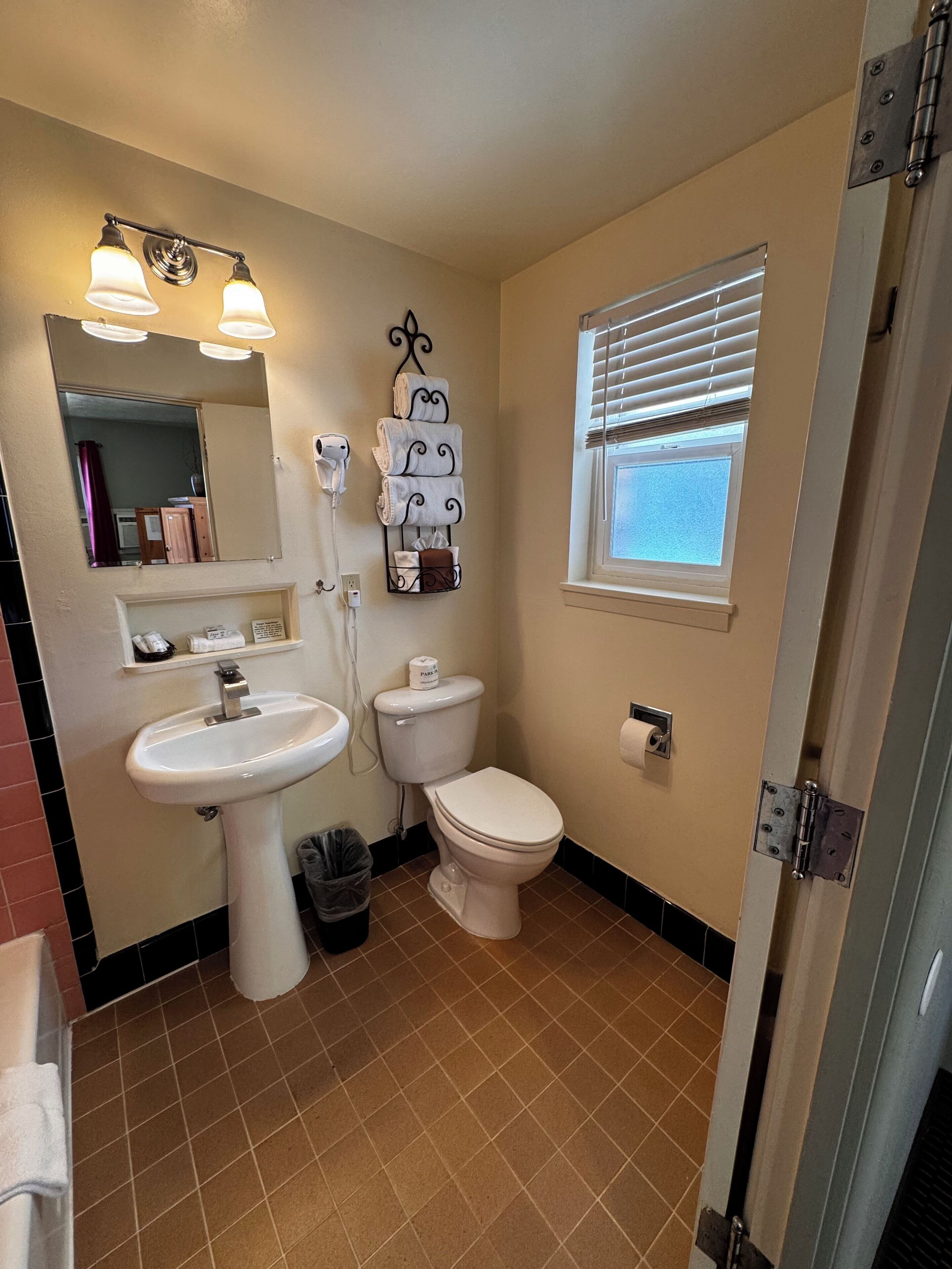 A bathroom with a sink, toilet, and a window with blinds.