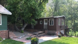 A cabin with a patio, a stone fireplace, and a small outdoor seating area. - Stone Mountain Lodge and Cabins (Lyons)
