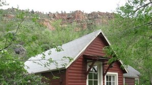 A small log cabin with a porch, a door, and a window. - Stone Mountain Lodge and Cabins (Lyons)