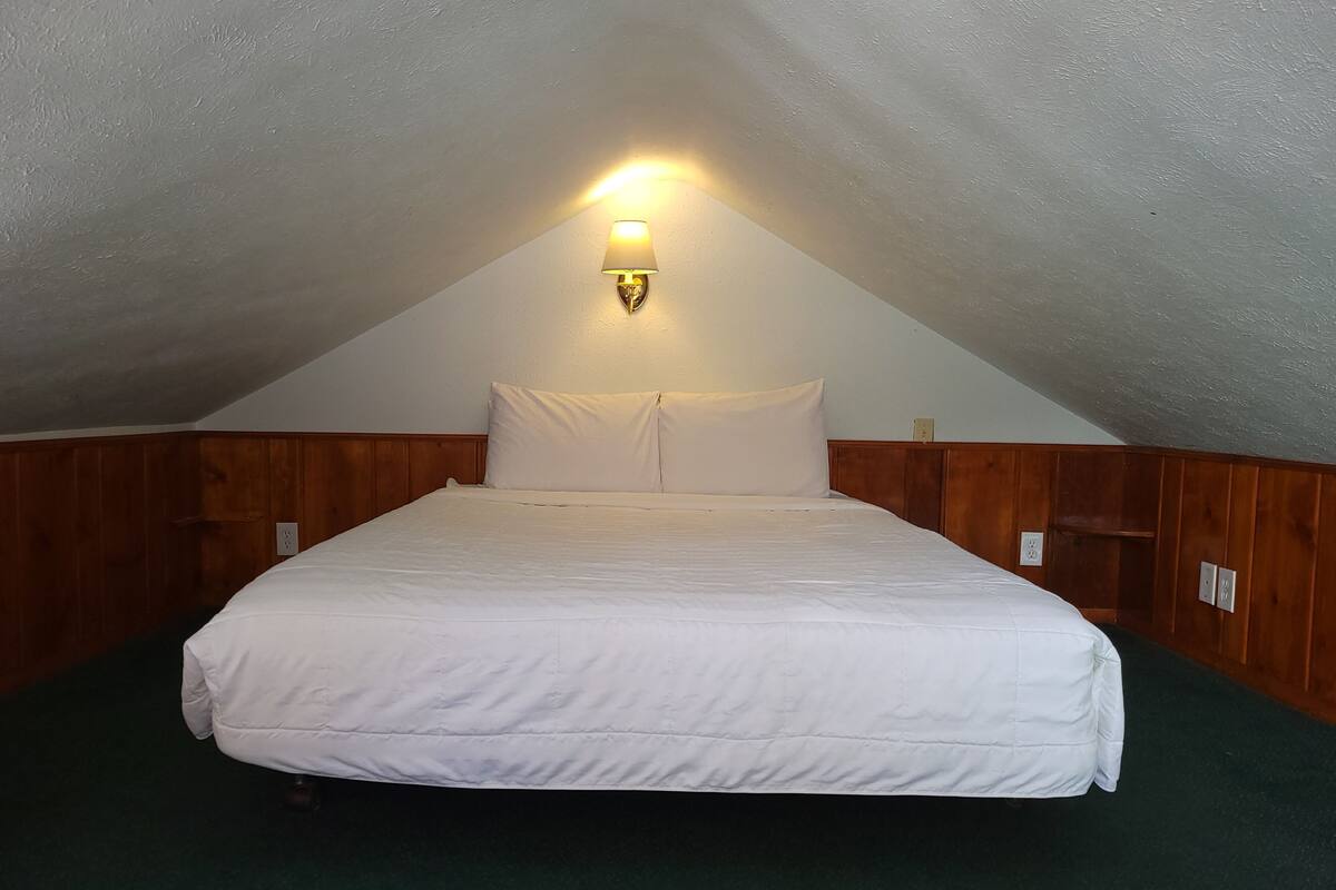 A single bed in a room with wooden paneling and a sloped ceiling.