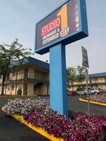 Un letrero de hotel que dice 'STUDIO OVERTIME & EXTENDED STAY' y un cartel de estacionamiento que indica 'MANTENERSE A LA DERECHA'.