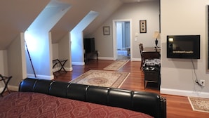 A spacious living area with a high ceiling, a fireplace, and a television mounted on the wall. - Magnolia Manor B&B Inn (Williamsburg)