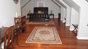 A bedroom with a large bed, a wooden dresser, a desk, and a chair. There is a large window with a view of the sky. - Magnolia Manor B&B Inn (Williamsburg)
