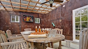 A wooden table with chairs, a pizza, and drinks in a covered outdoor area with a wooden ceiling and walls. - Bodega Bay Inn (Bodega Bay)