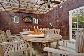 Enjoy a meal under the pergola with a wooden table and chairs.