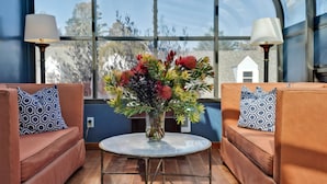 A room with two brown sofas, a round table, and a vase of flowers. - Bodega Bay Inn (Bodega Bay)