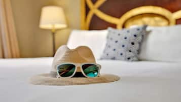 Una cama con una colcha blanca, un sombrero de paja y un par de gafas de sol.