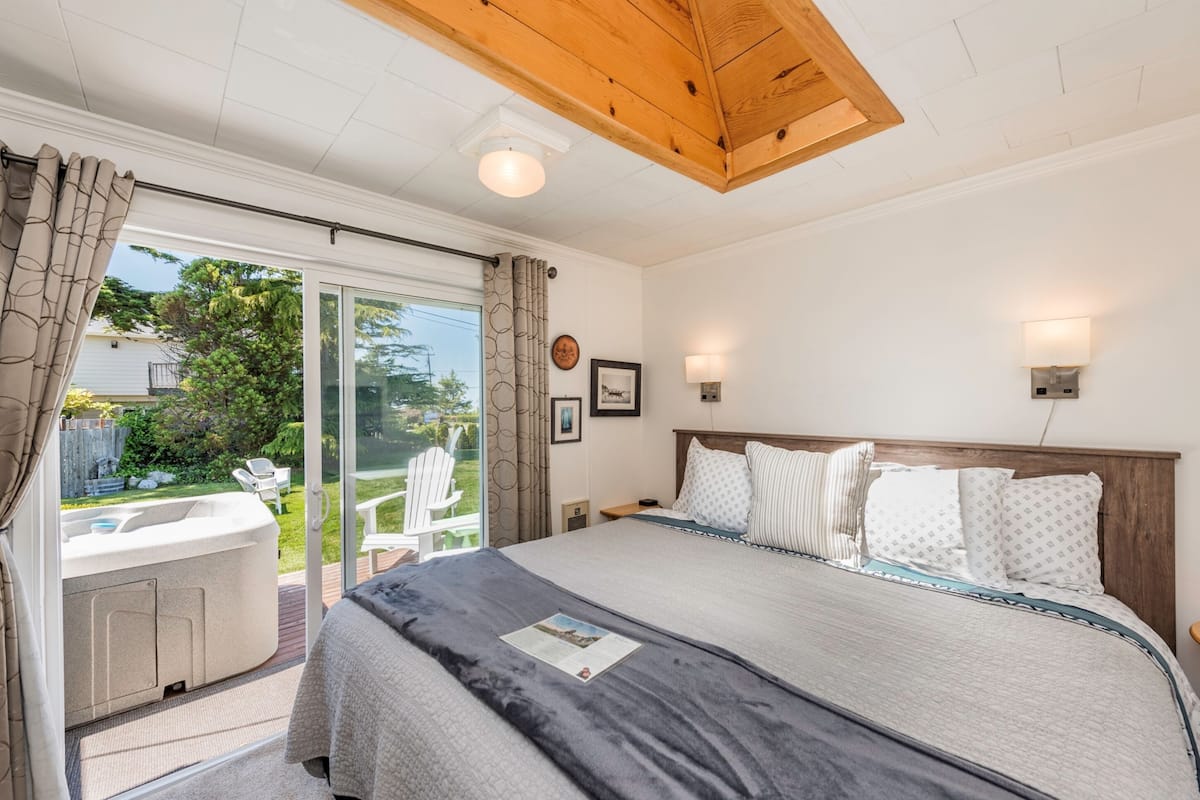 A bedroom with a large bed, a hot tub, and a sliding glass door leading to a patio.