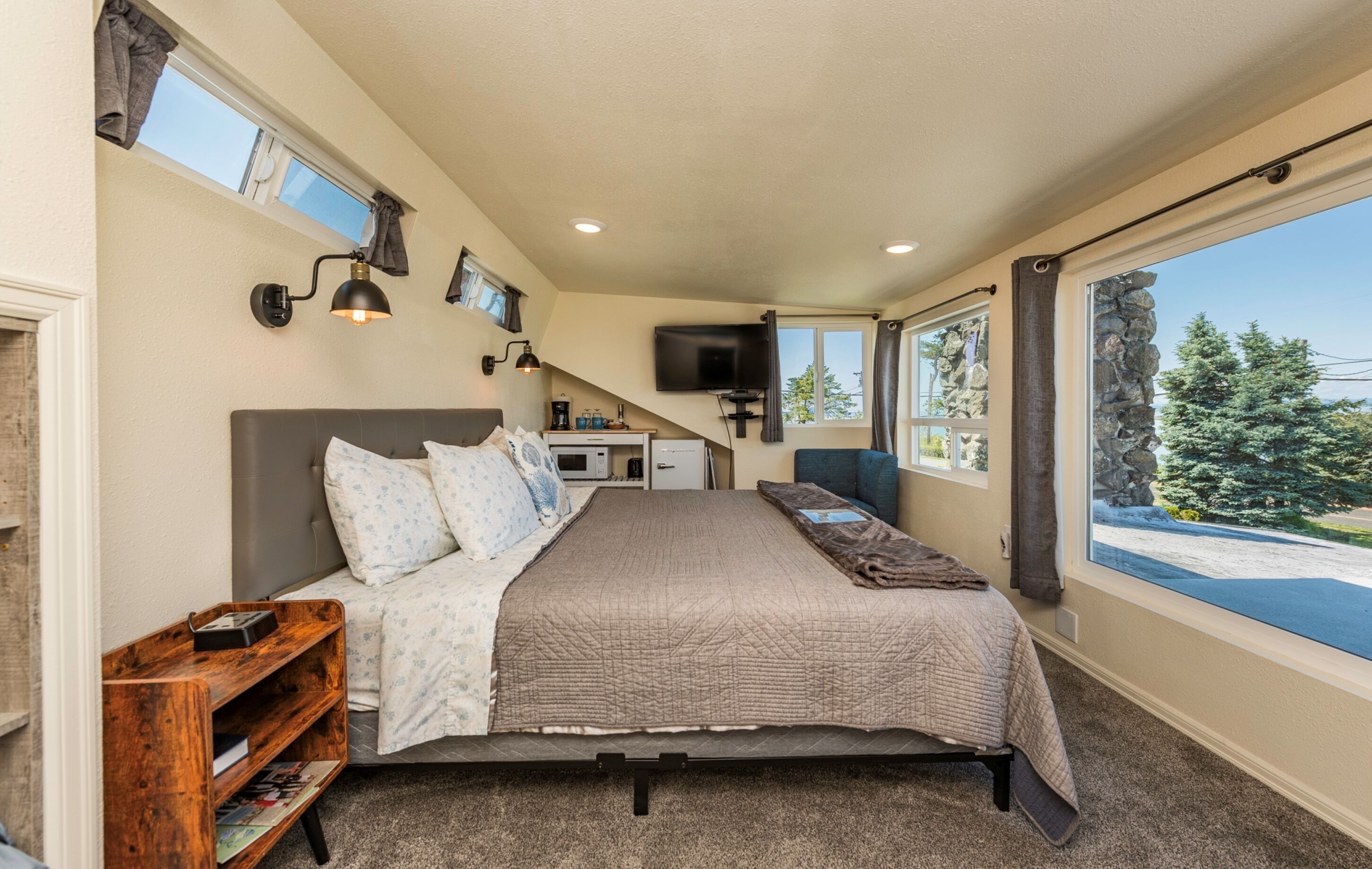 Un dormitorio con cama, mesita de noche y vistas al exterior.