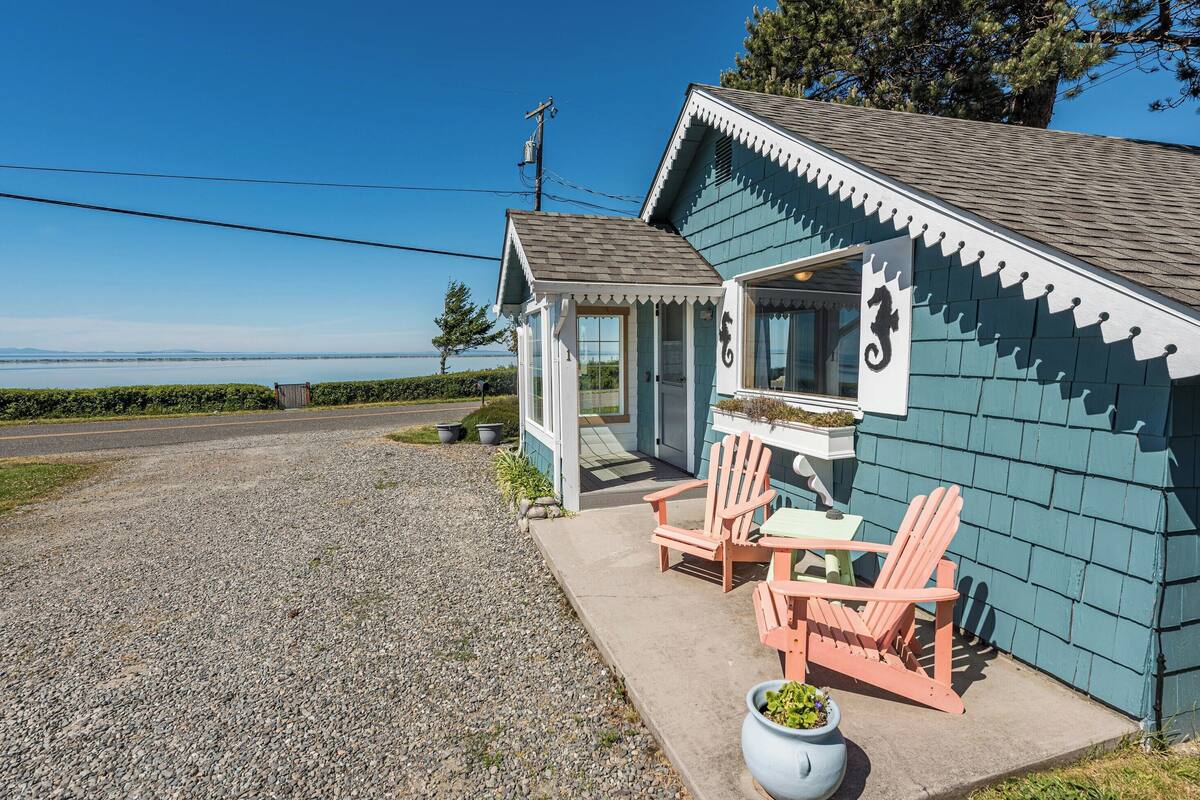 A small building with a porch, two chairs, and a table.