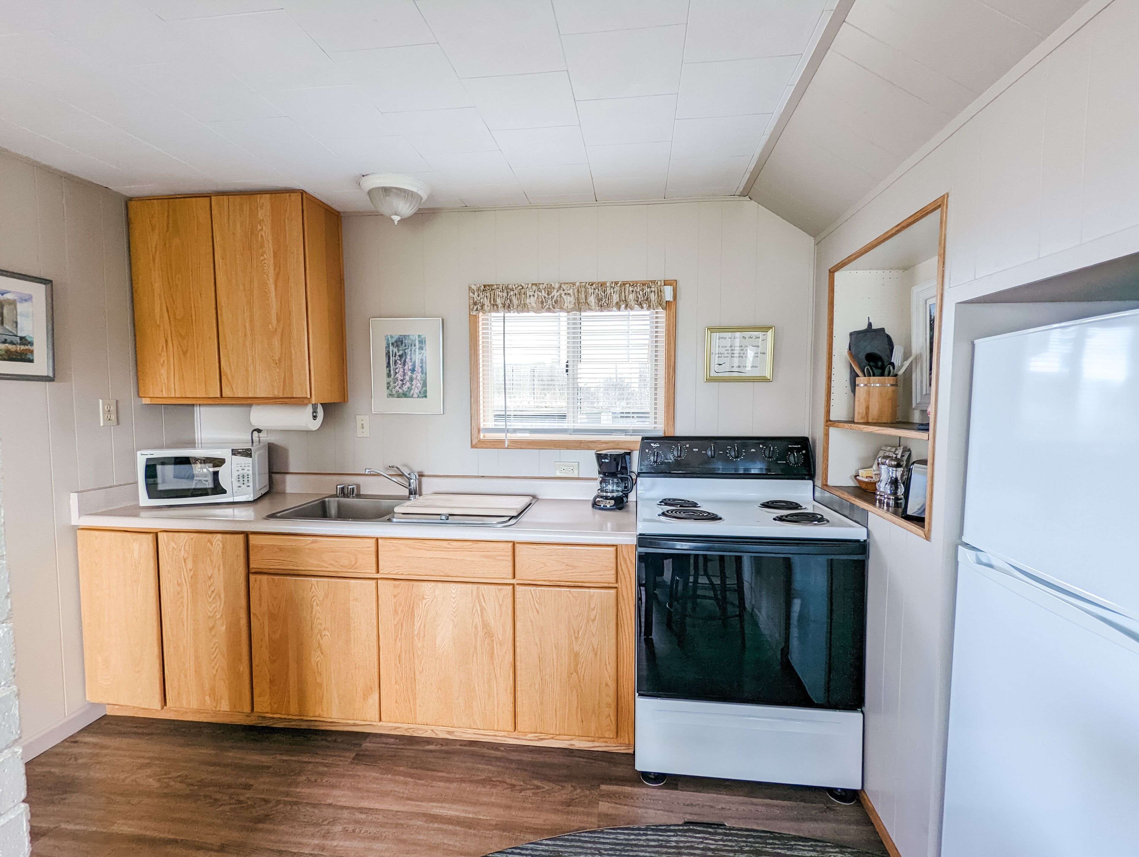Une cuisine de taille réduite, dotée de meubles en bois, d’un four à micro-ondes, d’une cuisinière et d’un réfrigérateur.