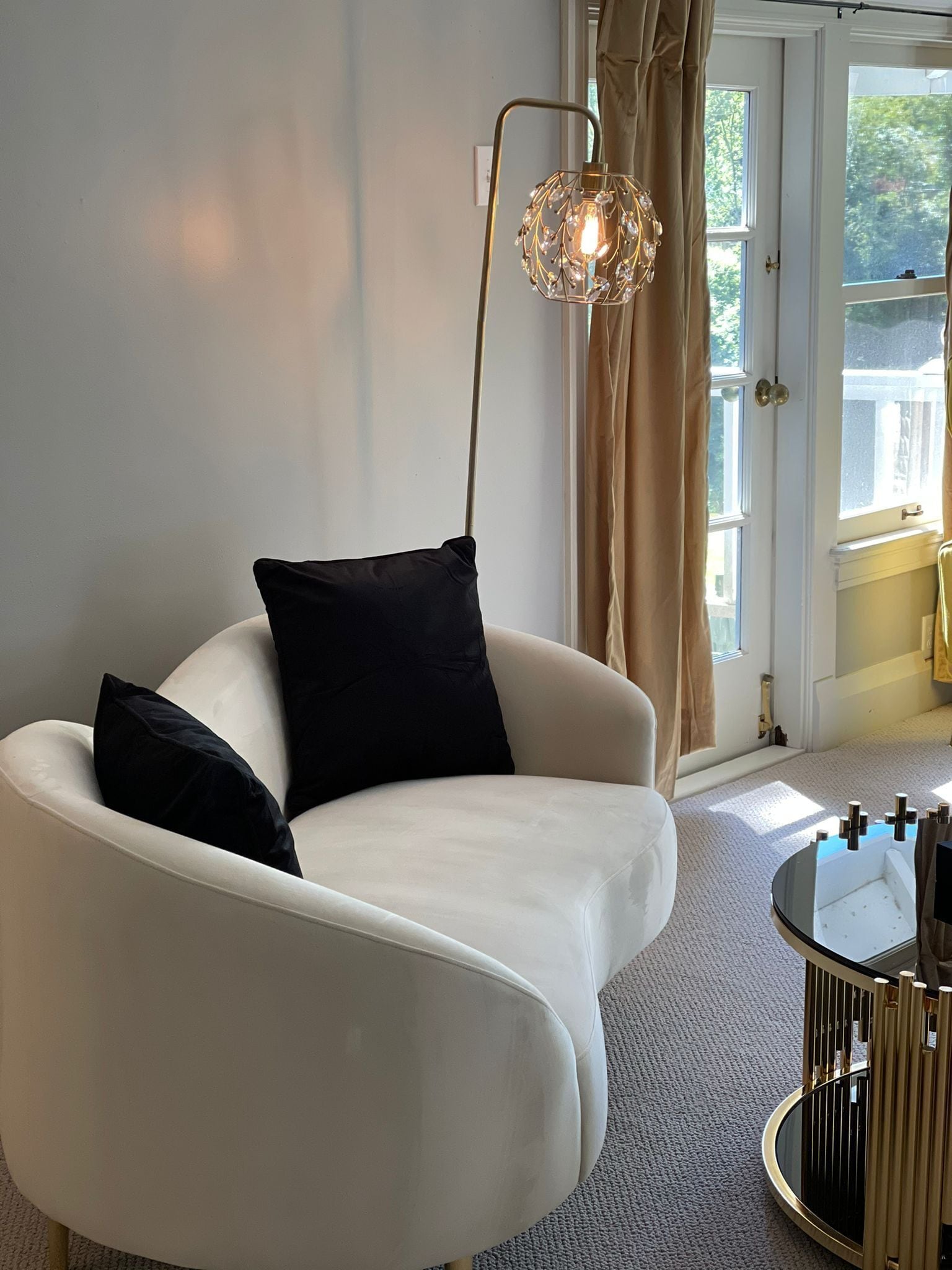A modern living room with a white armchair, a floor lamp, and a round coffee table.