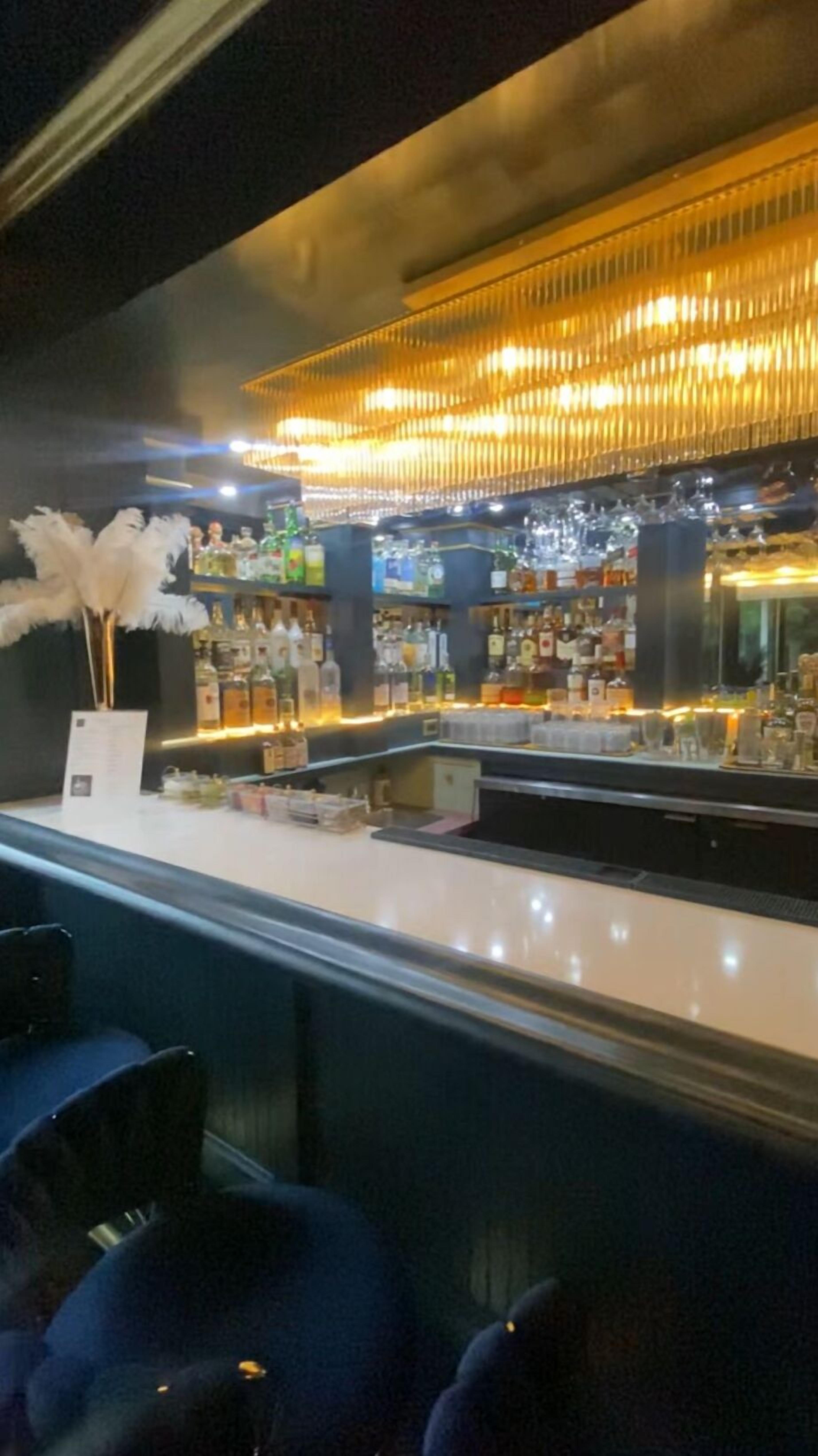 A bar area with a counter, shelves of liquor bottles, and a decorative feather arrangement.