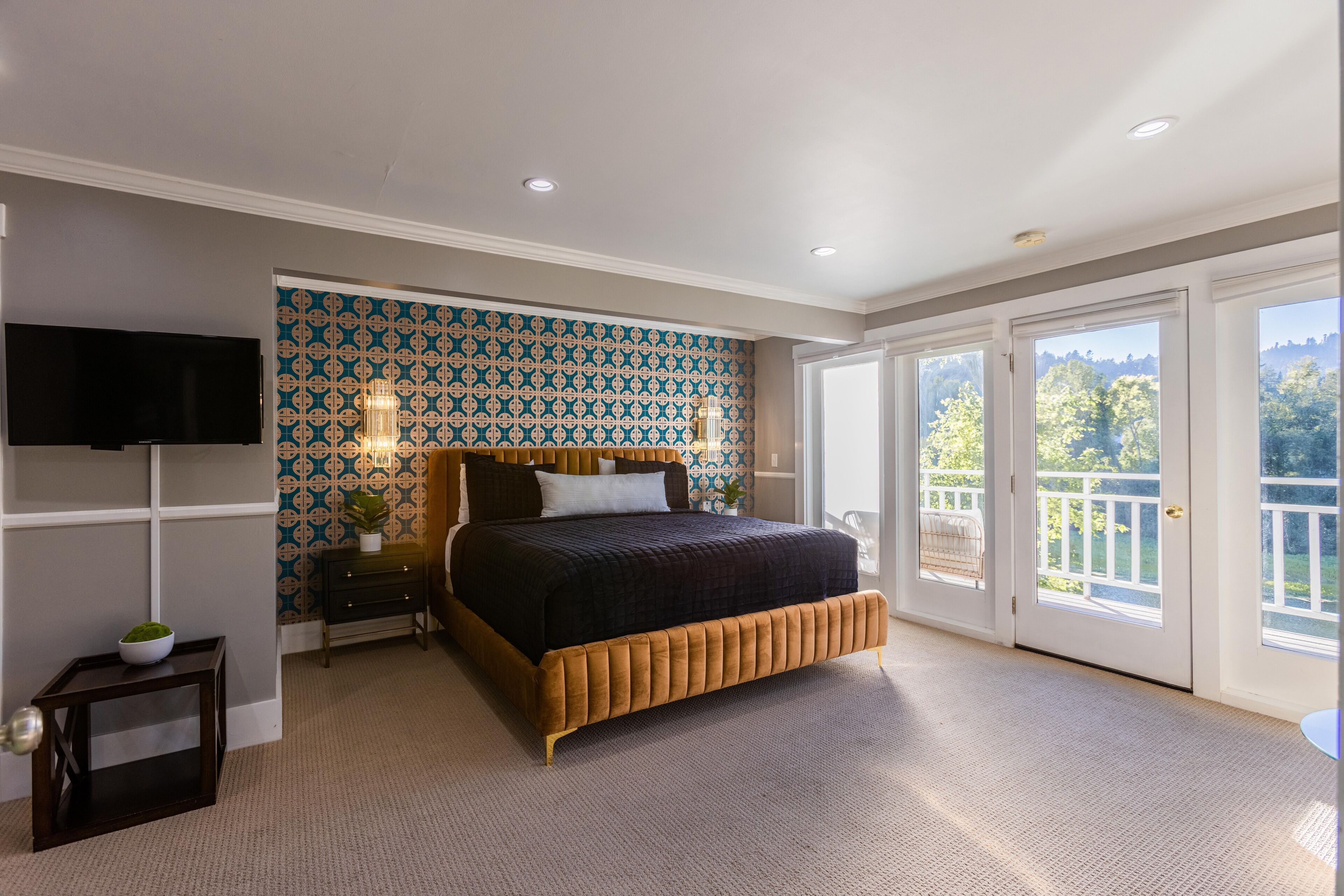 Une chambre avec un grand lit, une télévision et un balcon avec vue.