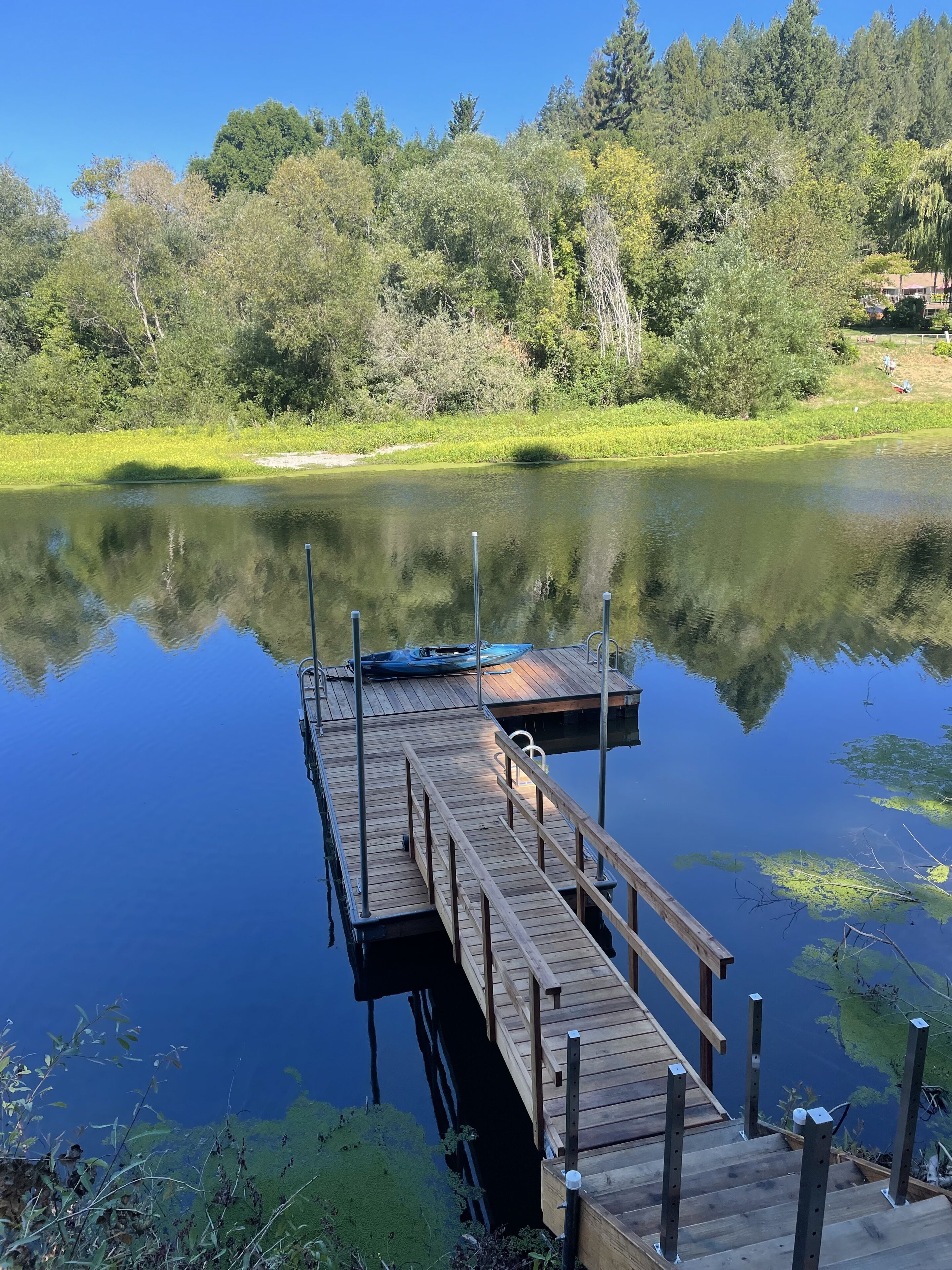 A wooden dock extending into a calm lake with a reflection of the surrounding trees.