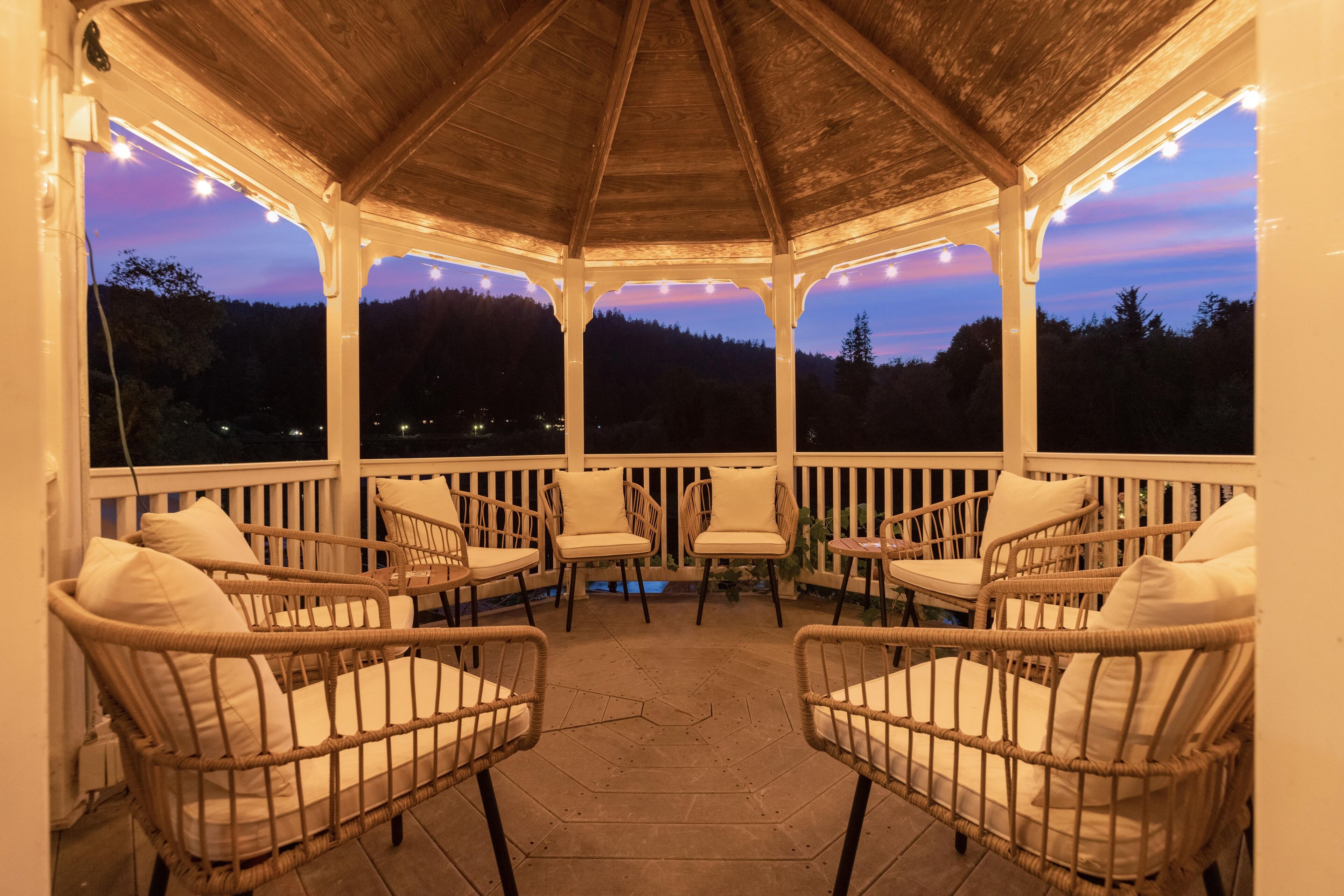 A covered outdoor seating area with wicker chairs and a wooden ceiling.