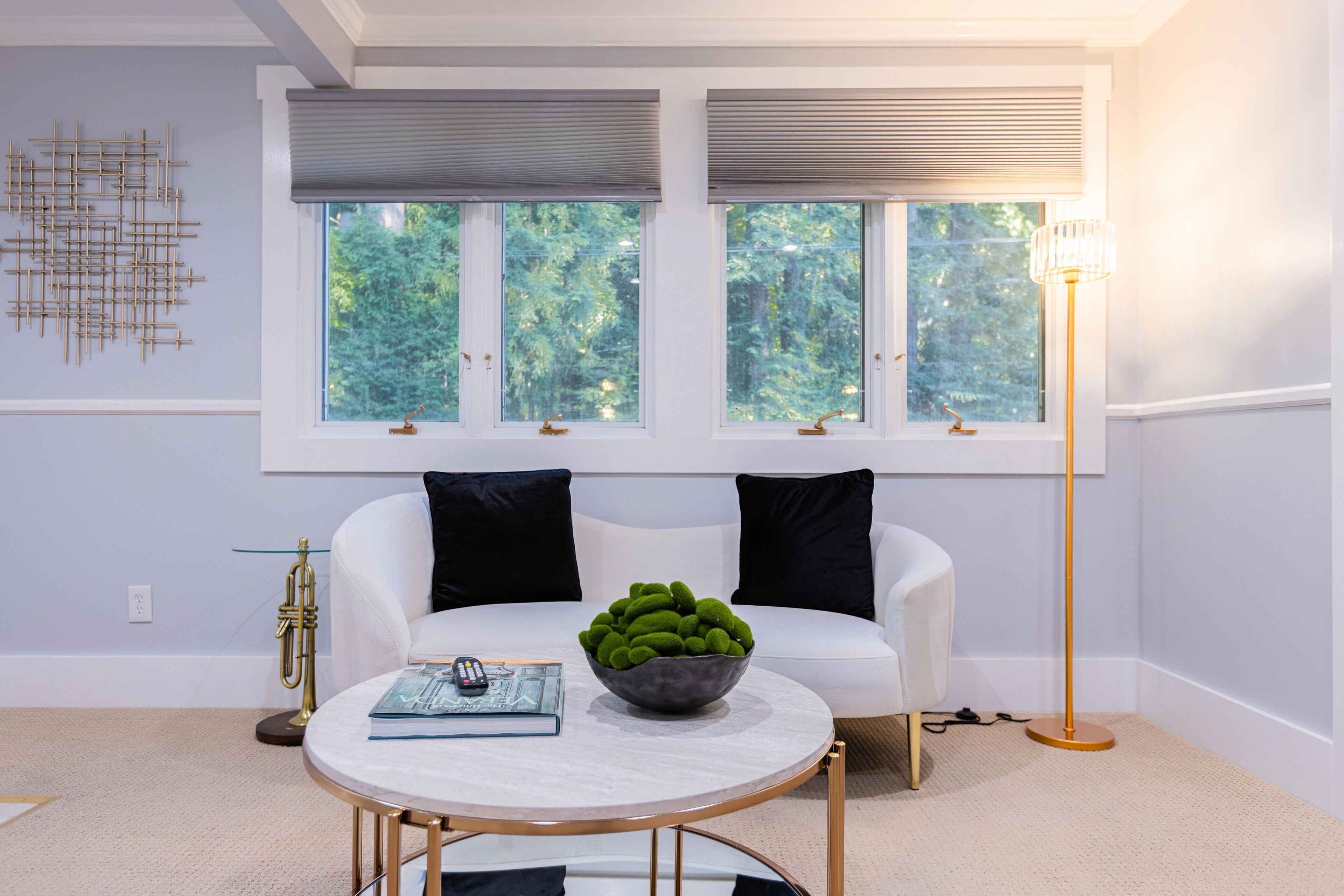 Un salon moderne avec un canapé blanc, une table basse ronde et un lampadaire.