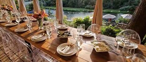 Een eettafel gedekt voor een maaltijd met uitzicht op een meer en groen.