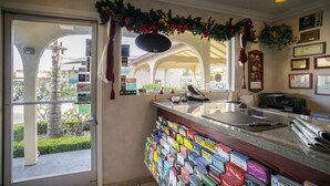 A reception area with a glass door, a counter with magazines, and a view of the outside. - Travelers Inn (South San Francisco)