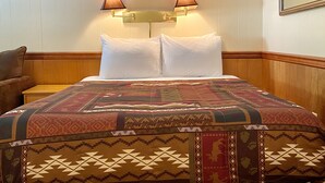Camera d'albergo con un letto, due lampade a parete e una testiera in legno.
