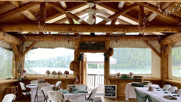 Un ristorante in stile baita di legno con tavoli apparecchiati, luci decorative e vista sulla natura.