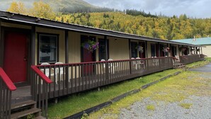 Un motel con un portico coperto, diverse camere e montagne sullo sfondo.