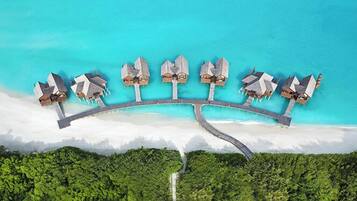 Vista aérea de un resort con una serie de bungalows sobre el agua conectados por un puente.