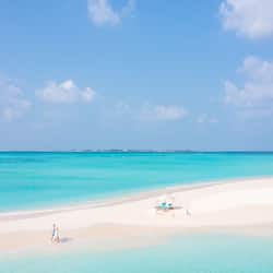 Relax on a wide, sandy beach with gentle waves, perfect for sunbathing or swimming.
