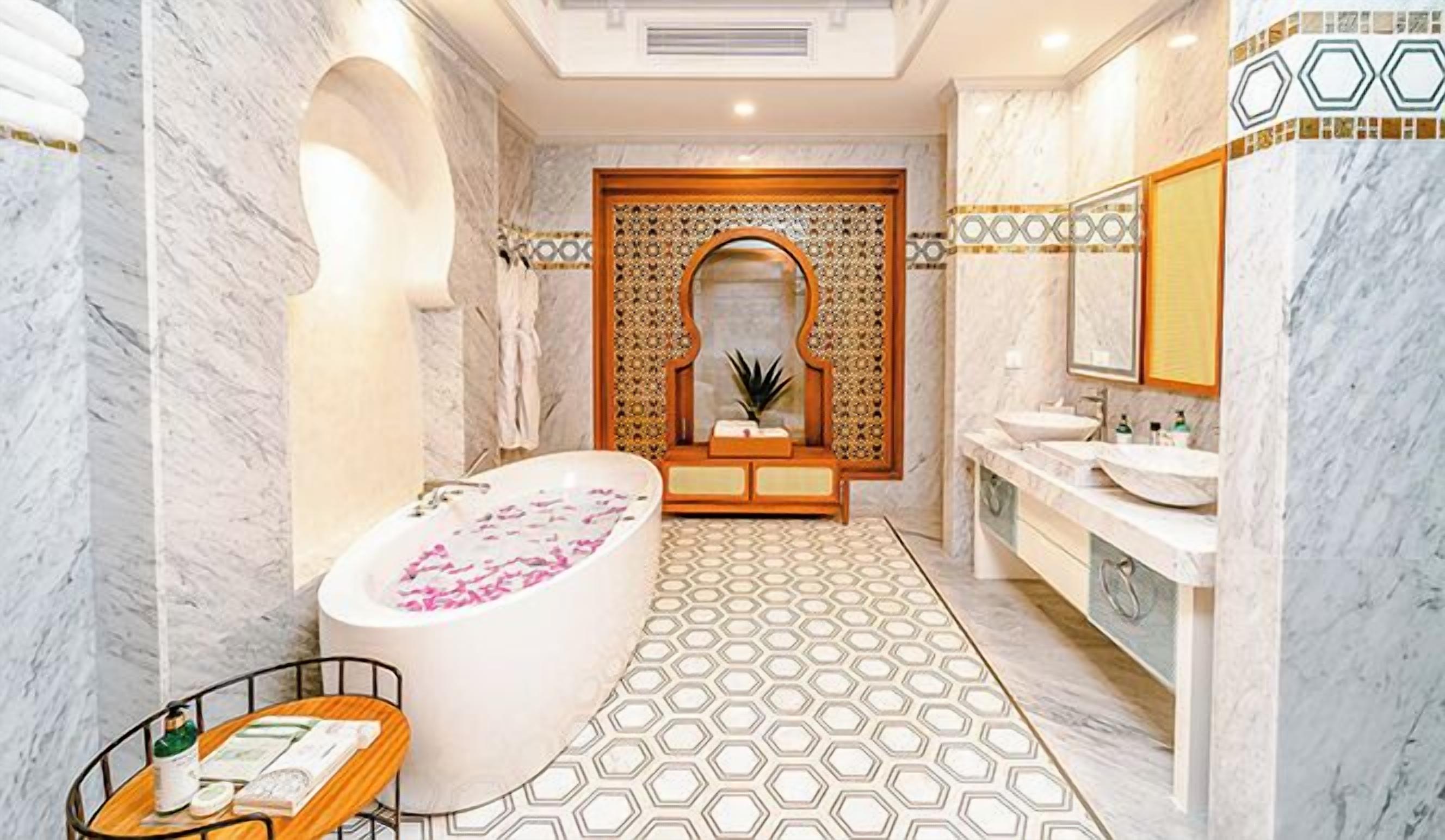 A luxurious bathroom with a freestanding bathtub, a large mirror, and a vanity with two sinks.