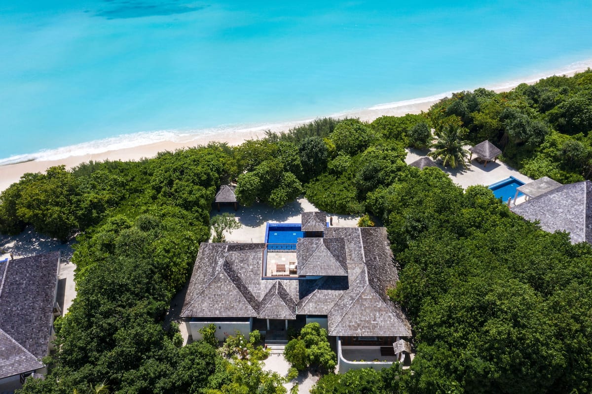 Vista aérea de un resort con varias edificaciones, una piscina y una playa.