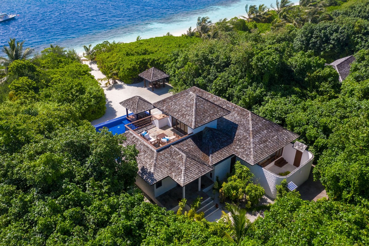 Vista aérea de un resort con piscina, varias construcciones y abundante vegetación.