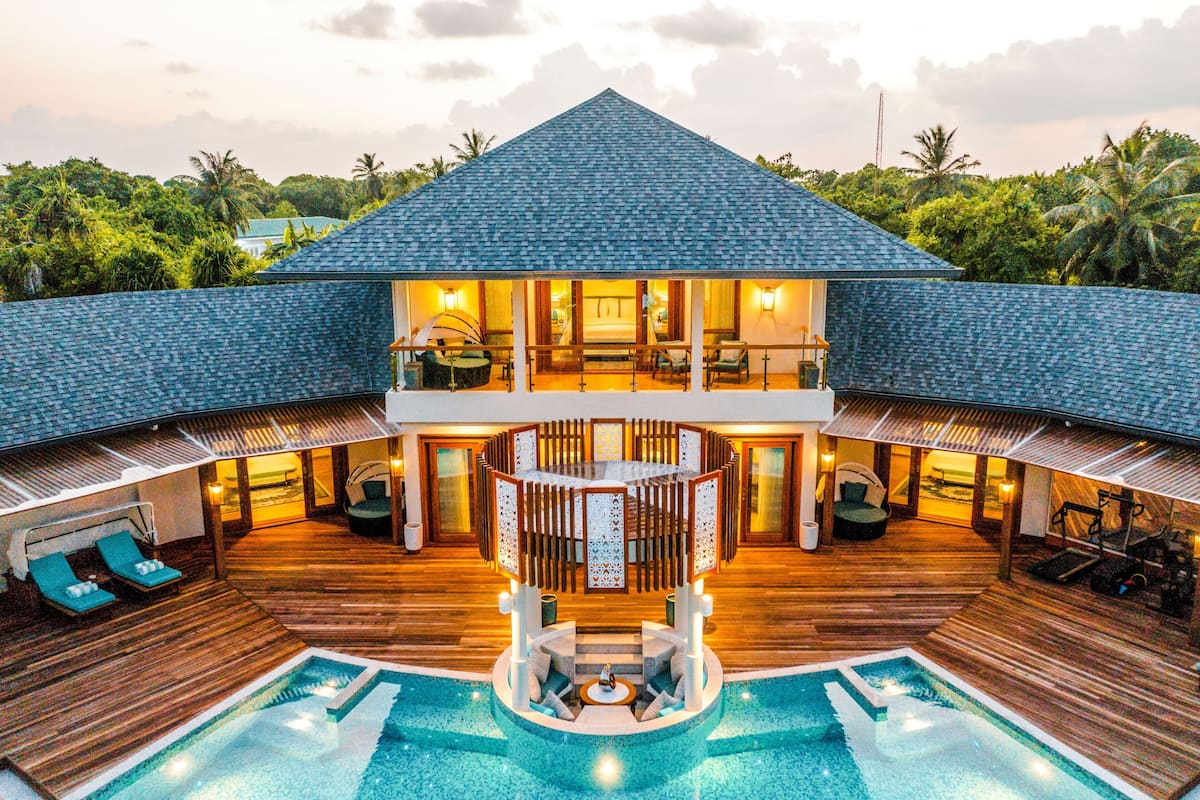 Un resort con piscina, terraza de madera y zona de estar cubierta con vista al océano.