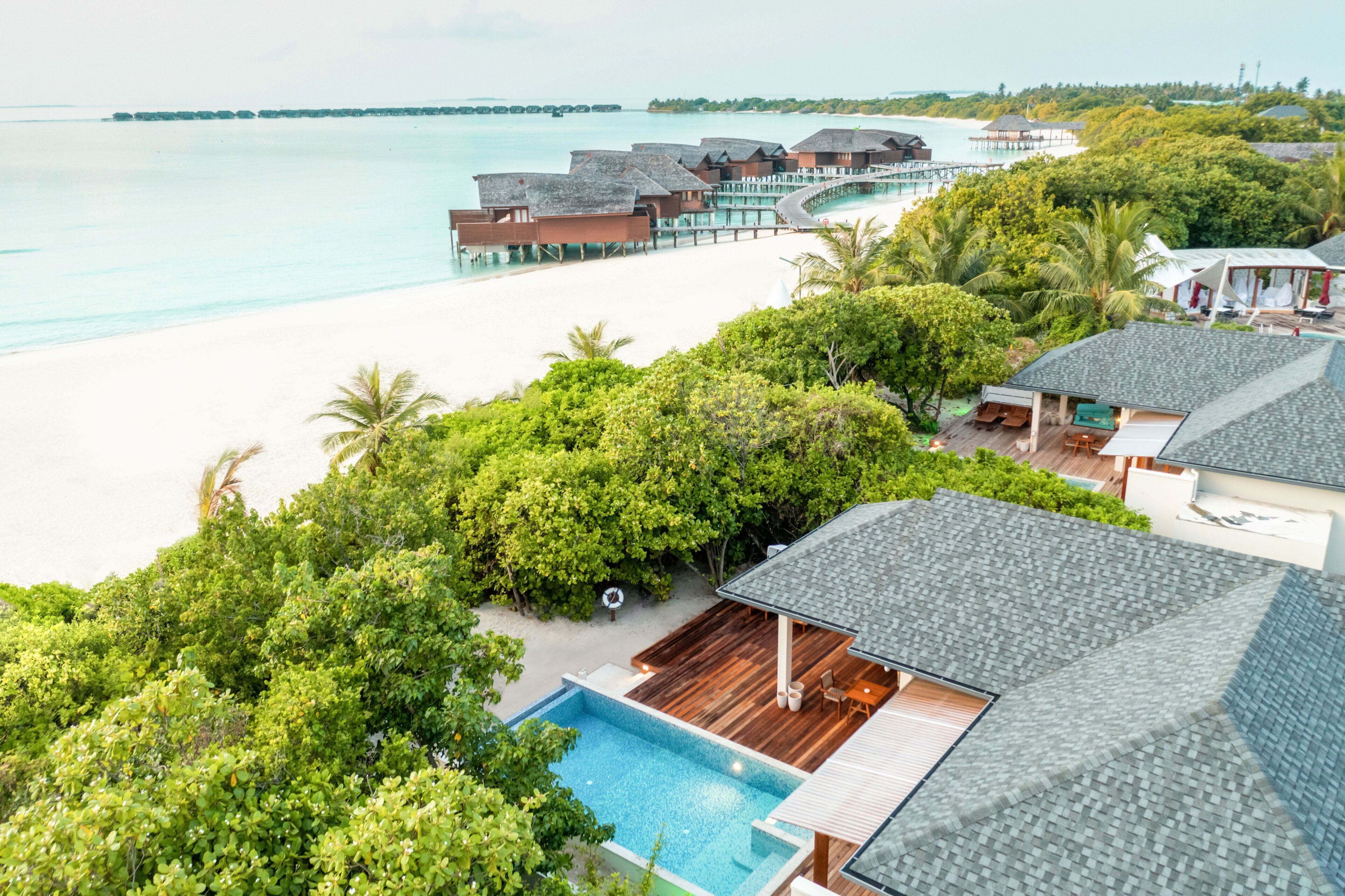 A resort with a pool, beach, and overwater bungalows.