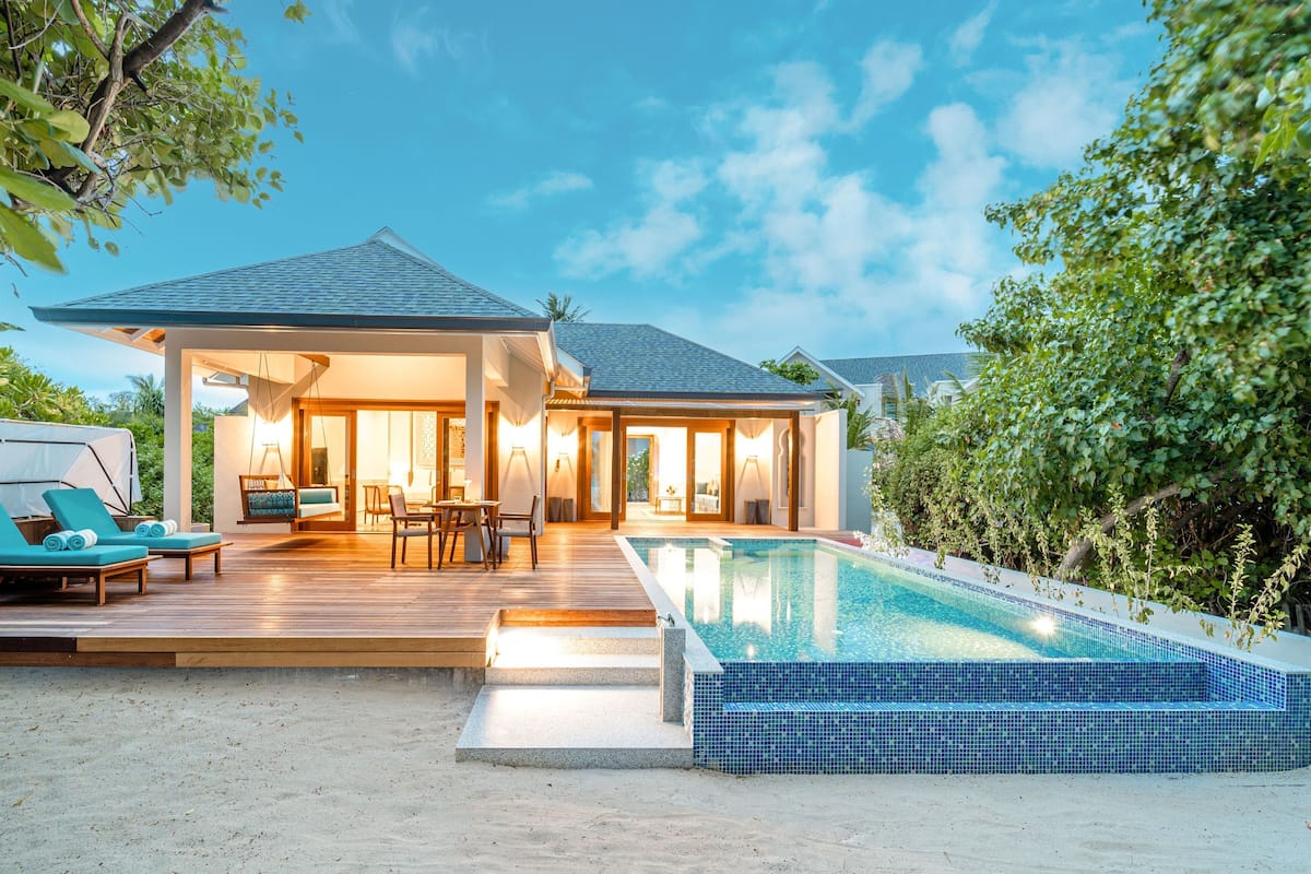 Una casa moderna con piscina, mobiliario exterior y un patio cubierto.