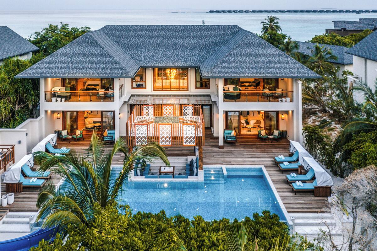 Un resort con una piscina grande, varios balcones y un tobogán.