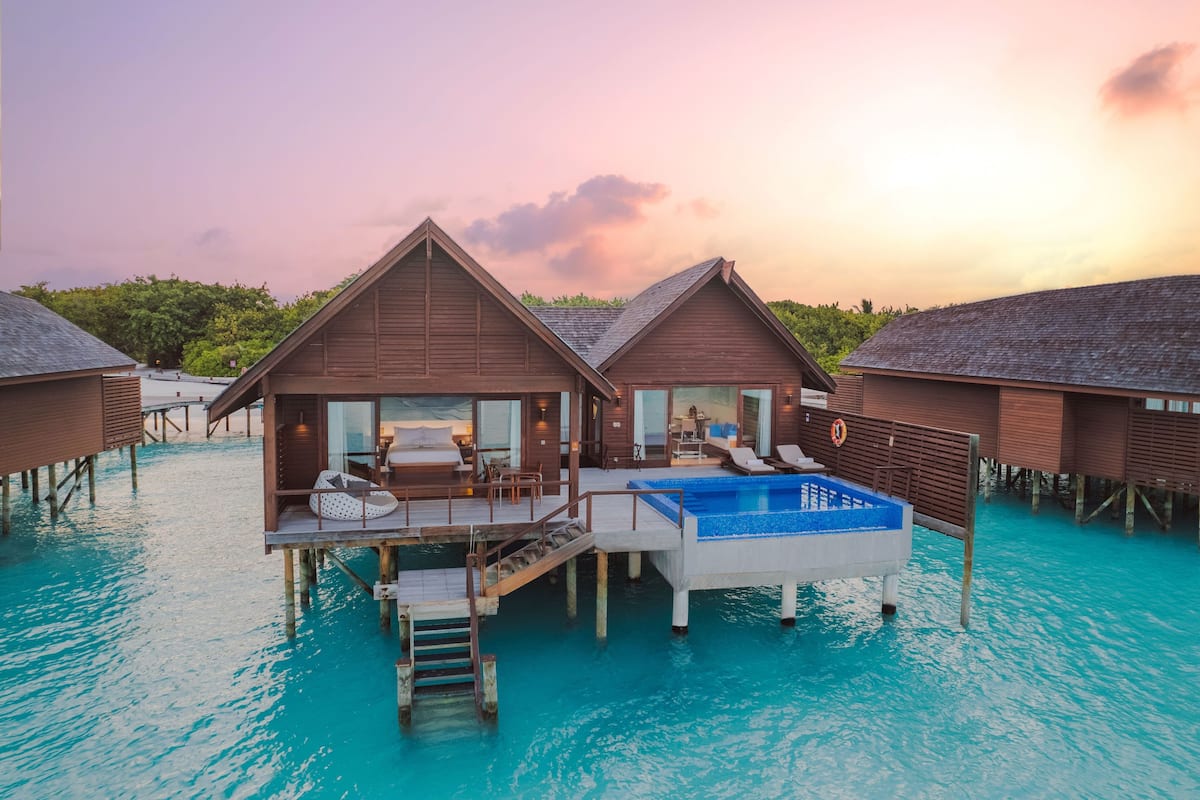 Bungalows sobre el agua con piscina, terraza de madera y puertas de cristal que dan al interior.