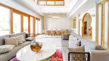 A spacious living area with a marble coffee table, grey sofas, and a dining area in the background.