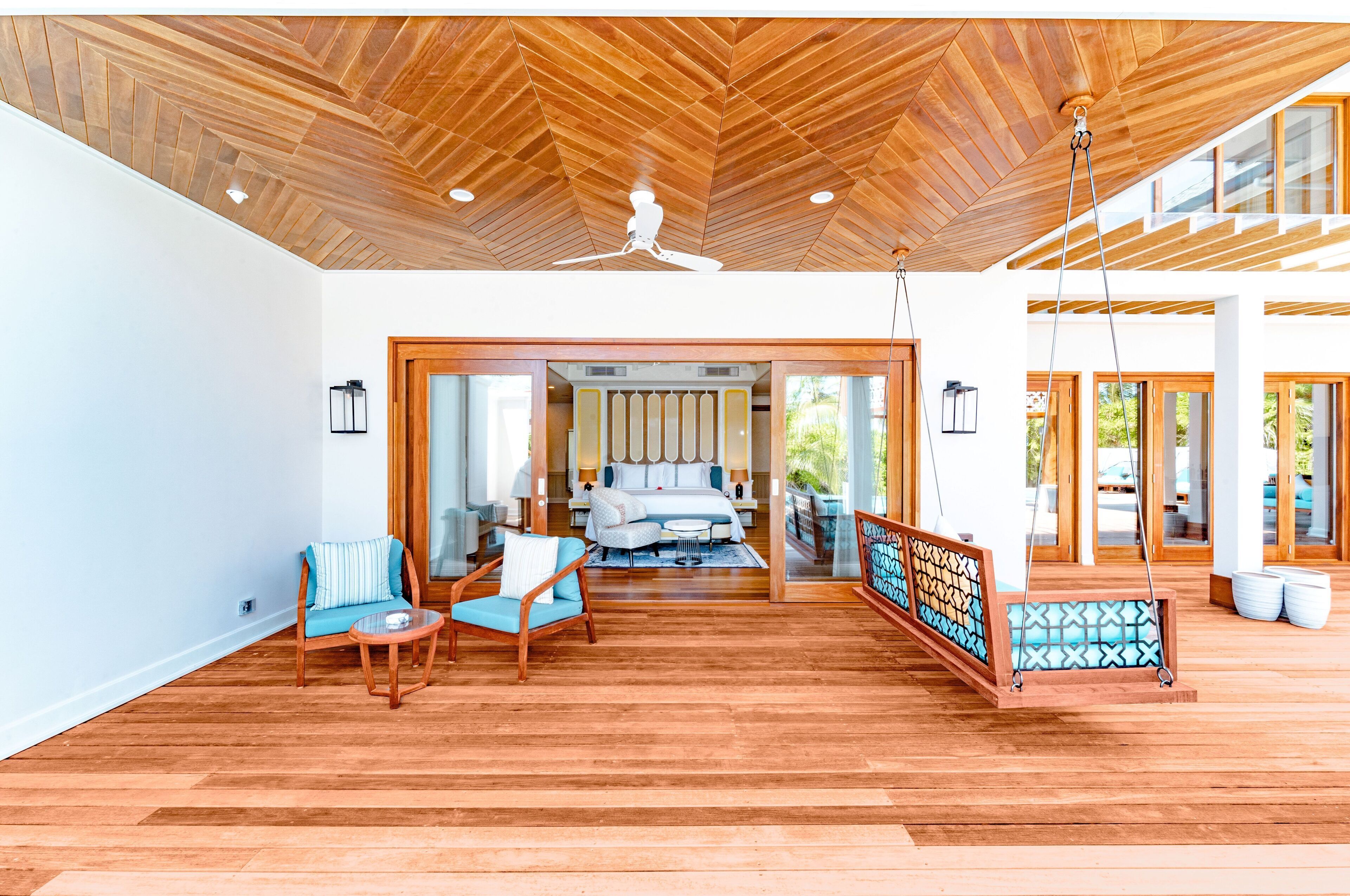 A spacious room with a wooden ceiling, a bed, a seating area with chairs, and a view of the outside.