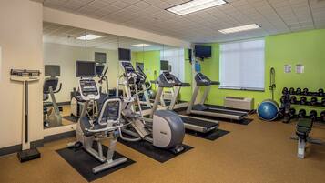 A gym with treadmills, elliptical machines, and a variety of weights.