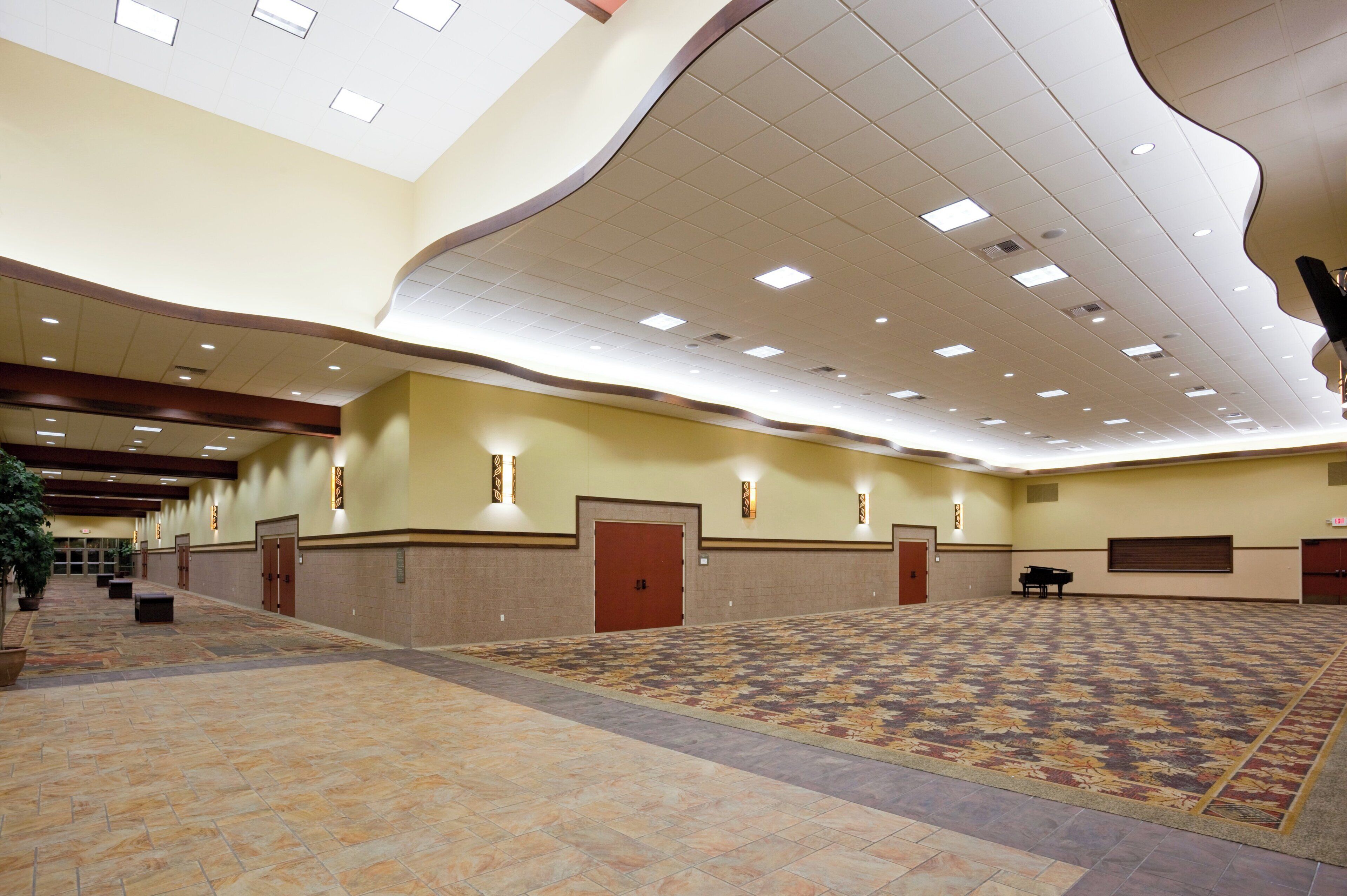 A spacious hall with patterned carpet, recessed lighting, and multiple doors.