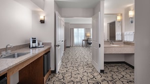 A hotel bathroom with a sink, mirror, and towel rack.