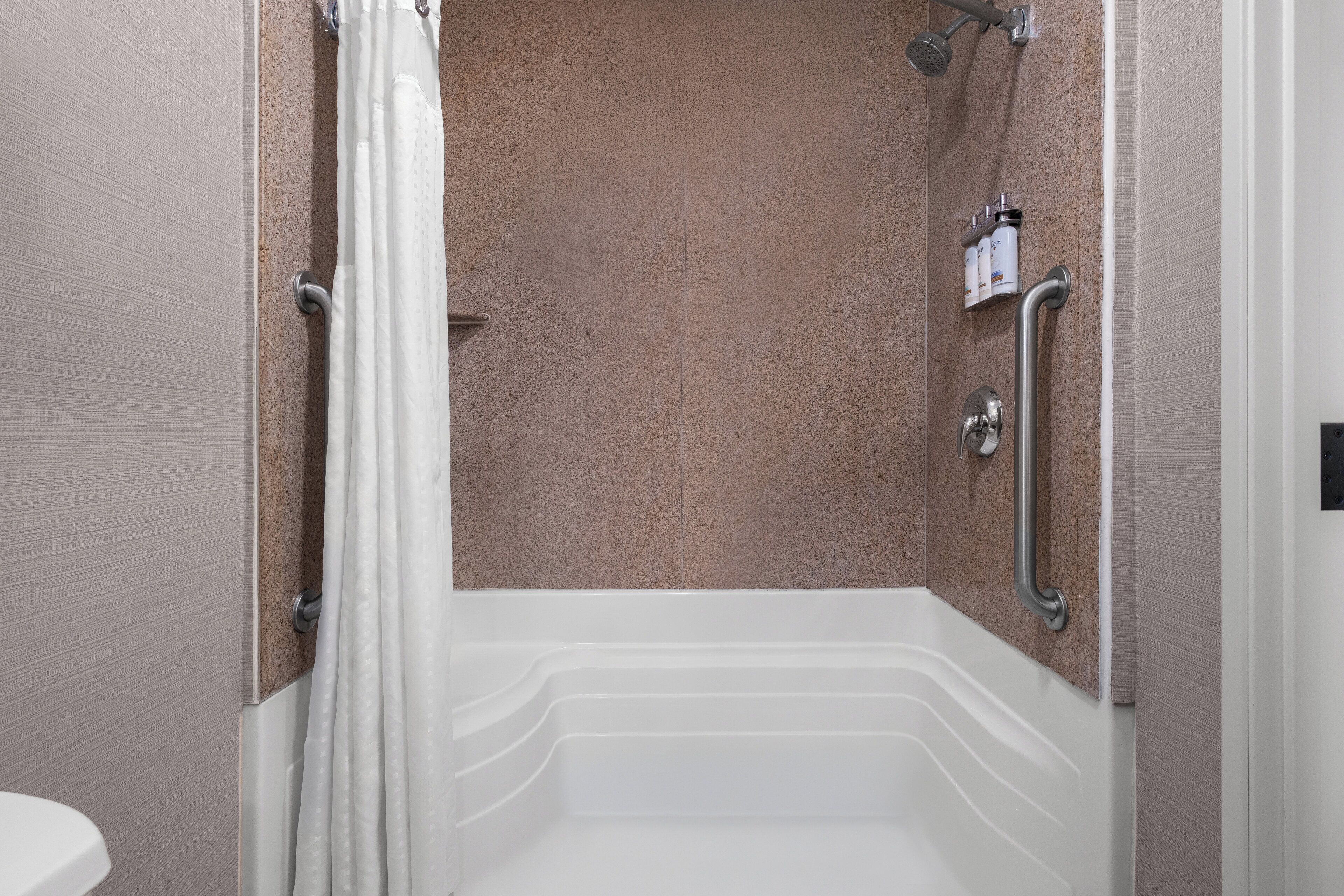 A modern bathroom with a shower, grab bars, and a toilet.