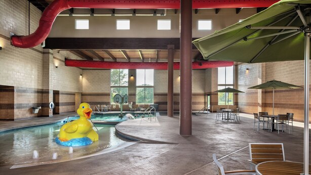 An indoor pool area with a duck float, seating, and a basketball hoop.