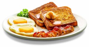 A plate with two fried eggs, toast, bacon, and a butter pat. - Holiday Inn Stevens Point - Convention Ctr by IHG (Stevens Point)