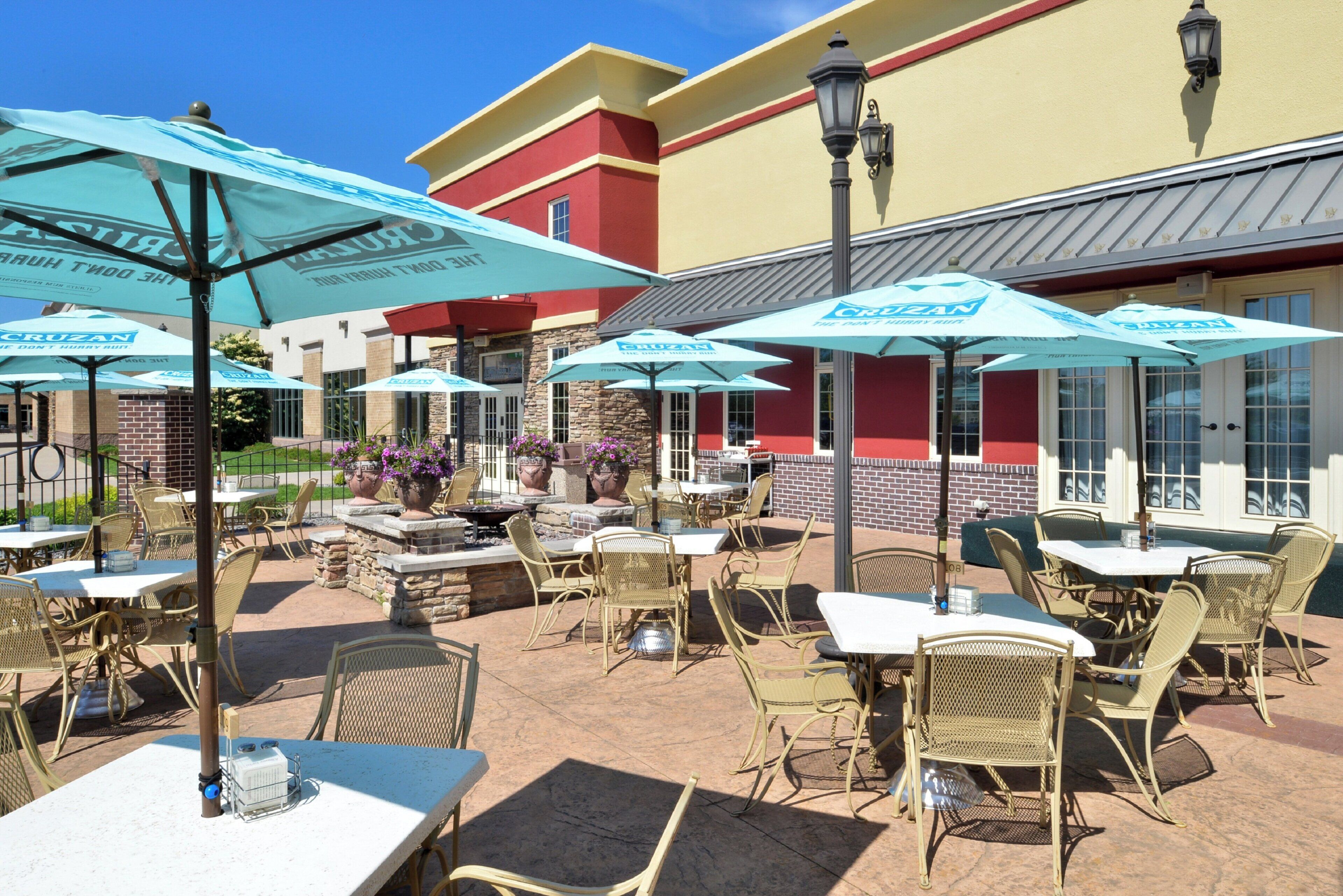 Un espace extérieur aménagé en terrasse, avec des tables et des chaises, des parasols, et un bâtiment en arrière-plan.