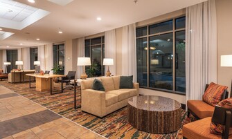 Un vestíbulo de hotel con mostrador de recepción, zona de estar y ventanas amplias.